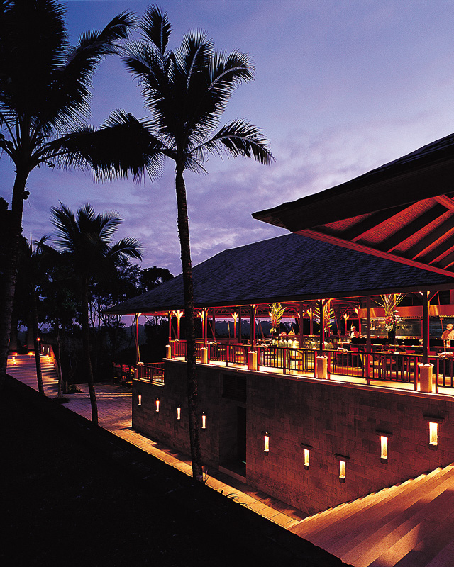 A view of Begawan Biji restaurant at dusk, with palm trees silhouetted against the sky.